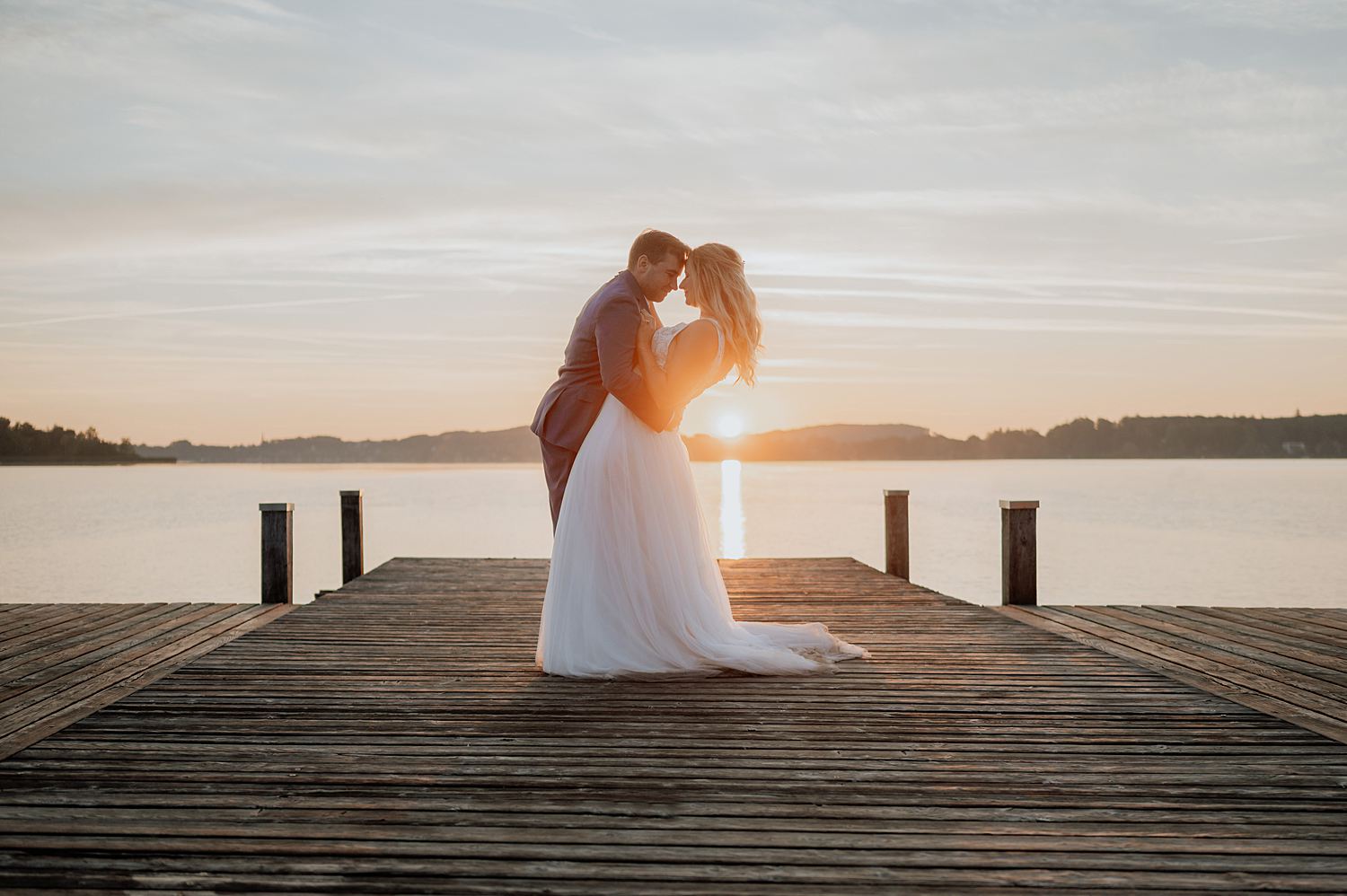 Wörthsee Hochzeitspaar steht einander beim Sonnenaufgang auf dem Steg gegenüber